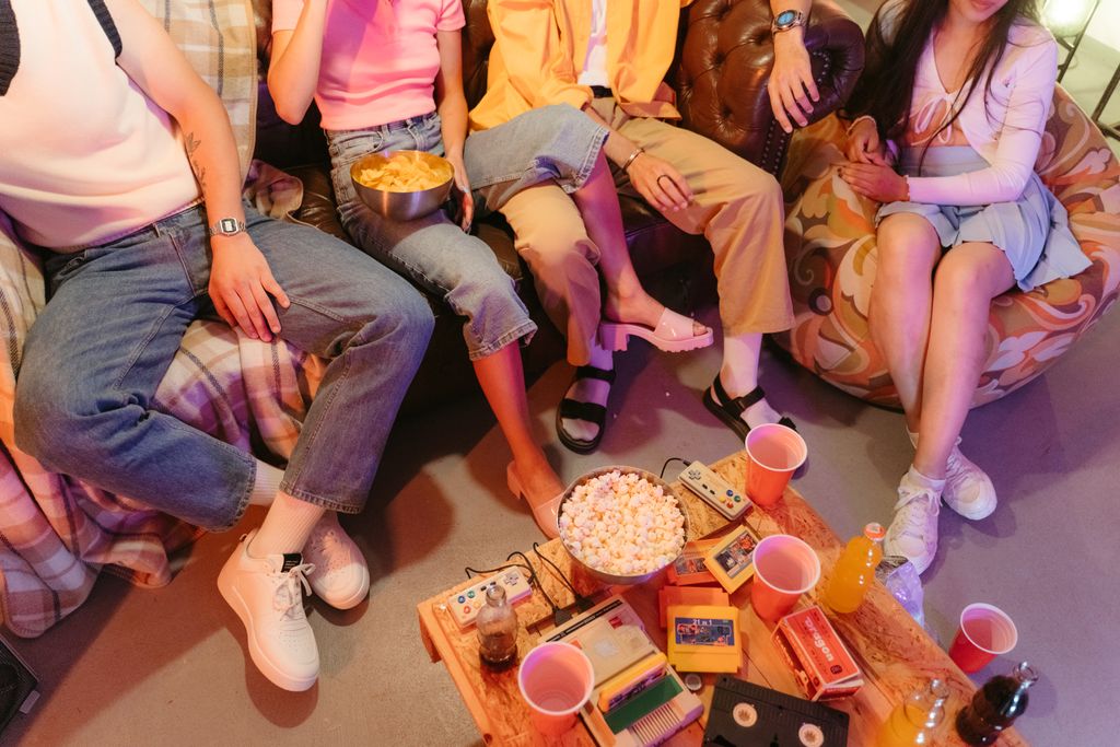 A close-up shot of friends enjoying snacks and drinks while sitting on a couch during a casual gathering.