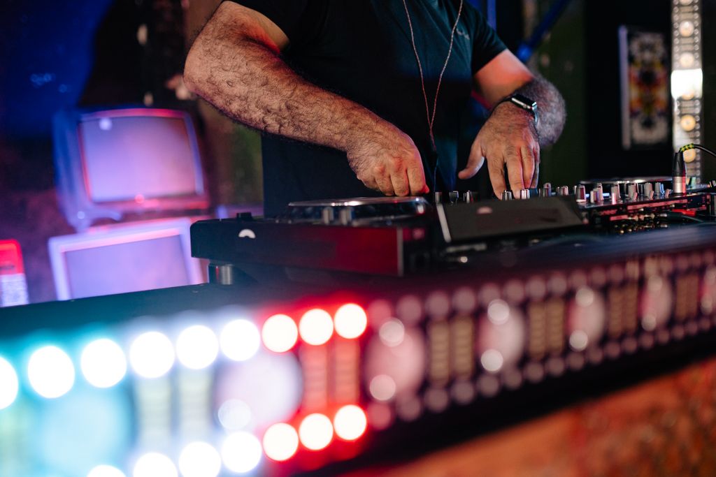 Close-up of a DJ mixing music at a lively nightclub event, creating an energetic party atmosphere.