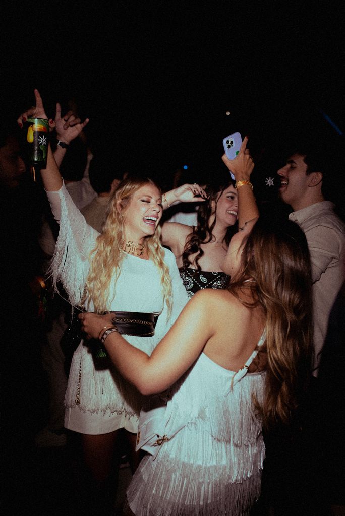 Group of friends enjoying a lively party at a nightclub, dancing and taking selfies.