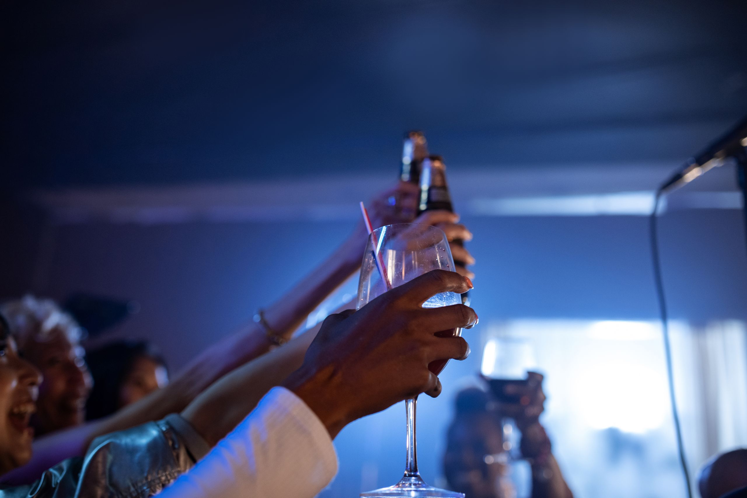 People raising glasses for a toast during a vibrant nightclub party.